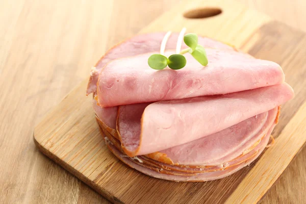 Smakelijke ham met zonnebloem spruiten op houten achtergrond — Stockfoto