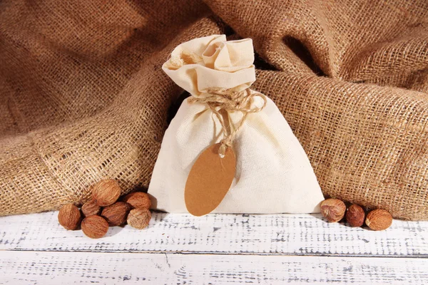 Sack full with spices, on wooden table, on sackcloth background — Stock Photo, Image
