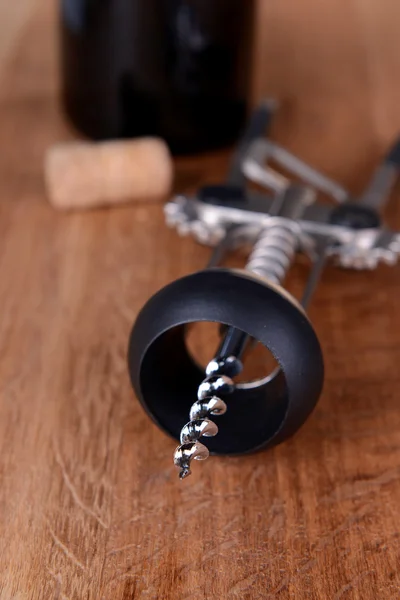 Corkscrew with bottle of wine on wooden background — ストック写真