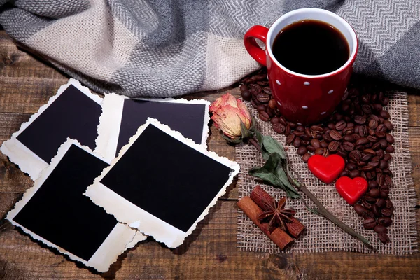 Komposition mit Kaffeetasse, dekorativen Herzen, karierten Gewürzen und alten Blankofotos, auf Holzgrund — Stockfoto