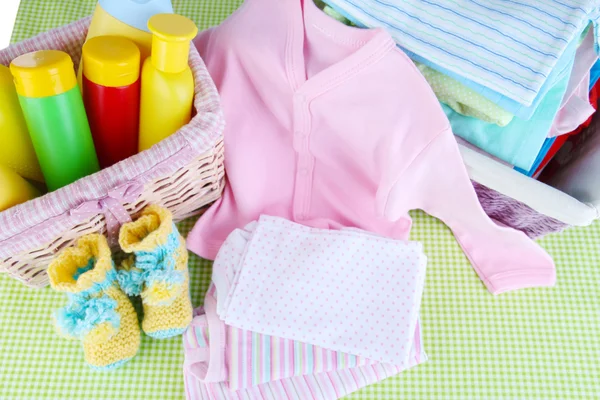 Pile of baby clothes  in basket, on table on color background — Stock Photo, Image