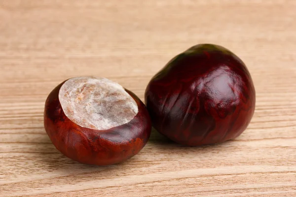 Castanhas marrons em fundo de madeira — Fotografia de Stock