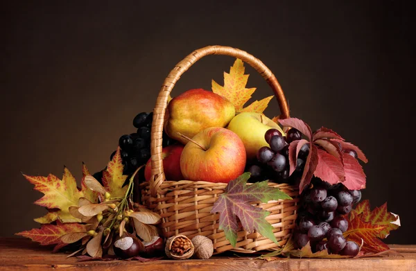 Hermosa cosecha de otoño en cesta y hojas sobre fondo marrón — Foto de Stock
