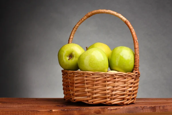 Ζουμερά πράσινα μήλα στο καλάθι στο ξύλινο τραπέζι σε γκρι φόντο — Φωτογραφία Αρχείου