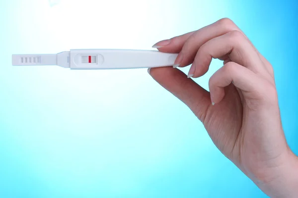 Hamilelik testi elinde mavi zemin üzerine — Stok fotoğraf