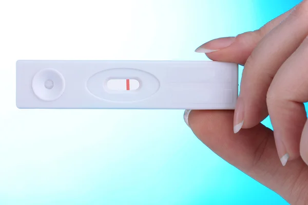 Pregnancy test in hand on blue background — Stock Photo, Image