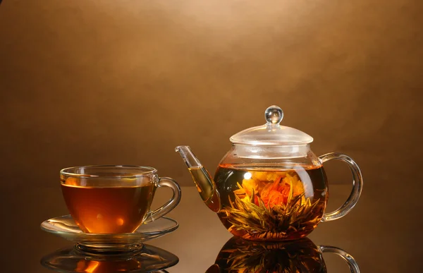 Glass teapot and cup with exotic green tea on wooden table on brown background — Stock Photo, Image