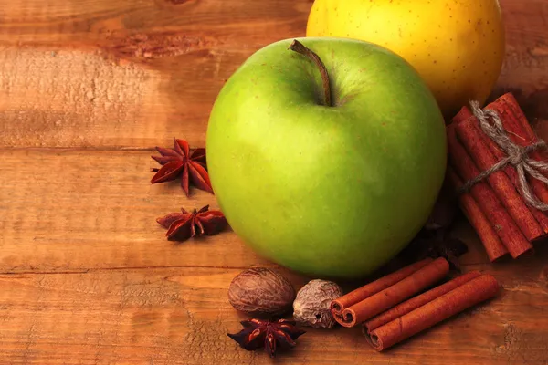 Tyčinky skořice, jablka, muškátový oříšek a anýzu na dřevěný stůl — Stock fotografie