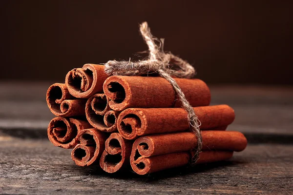 Bastoncini di cannella su tavolo di legno su sfondo marrone — Foto Stock