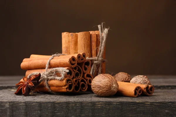 Palitos de canela, nuez moscada y anís sobre mesa de madera sobre fondo marrón —  Fotos de Stock