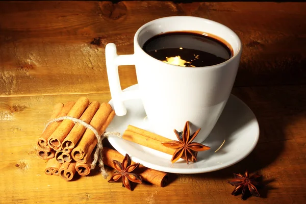 Kopp varm choklad, kanelstänger, nötter och choklad på träbord — Stockfoto