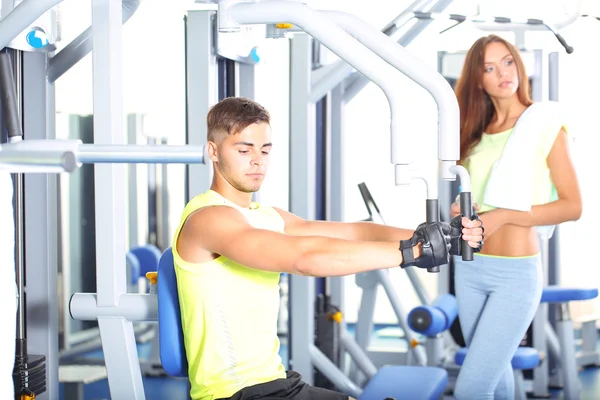 Guy and girl engaged in simulator at gym — Stock Photo, Image