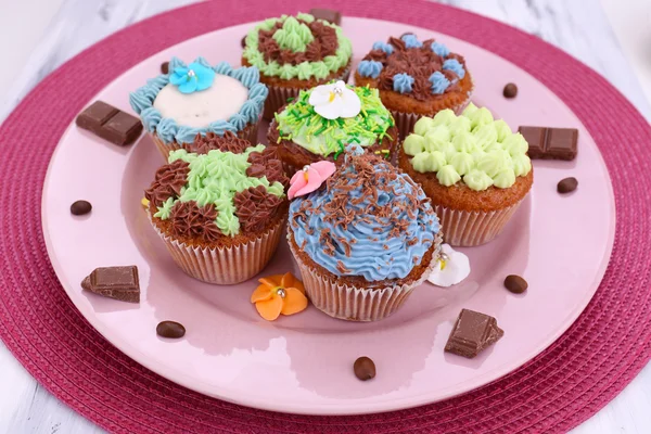 Leckere Cupcakes mit Buttercreme, auf Teller, auf Farbserviette, auf Farbholzhintergrund — Stockfoto