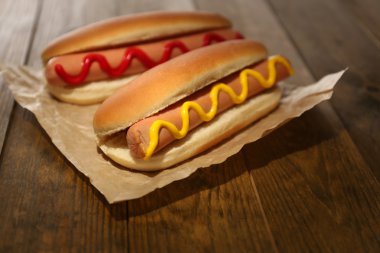 Tasty hot dogs on wooden table clipart