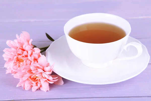 Pink chrysanthemums and cup of tea on wooden table — Stock Photo, Image