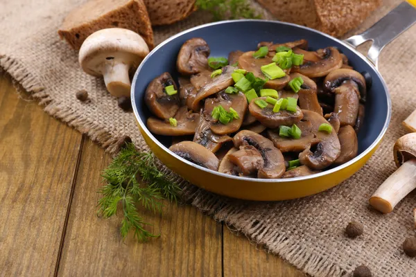 Heerlijke gebakken champignons in pan op tafel close-up — Stockfoto