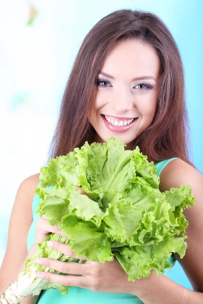 Hermosa chica con ensalada fresca sobre fondo azul — Foto de Stock