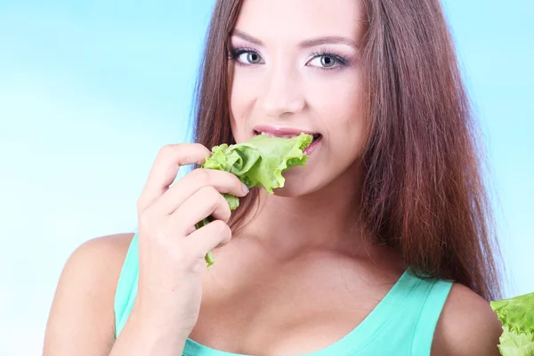 Hermosa chica con ensalada fresca sobre fondo azul — Foto de Stock