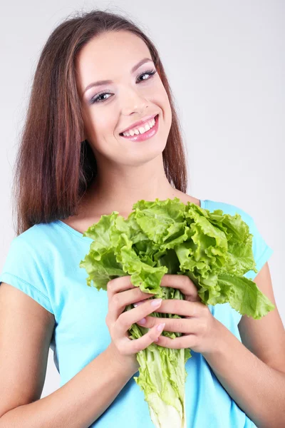 Beautiful girl with fresh salad on grey background — Stock Photo, Image