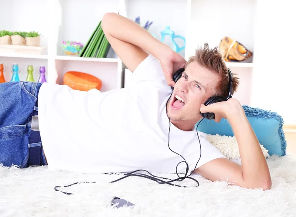 Young man relaxing on carpet and listening to music — Stock Photo, Image