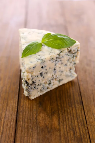 Tasty blue cheese with basil, on wooden table — Stock Photo, Image