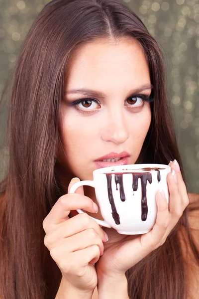 Retrato de hermosa joven con taza de chocolate caliente sobre fondo brillante — Foto de Stock