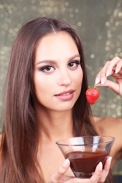 Retrato de hermosa joven con fresa en chocolate sobre fondo brillante —  Fotos de Stock