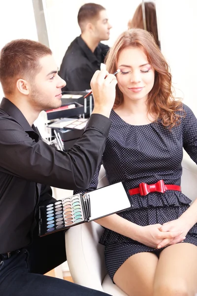 Jovem estilista fazendo maquiagem mulher bonita no salão de beleza — Fotografia de Stock