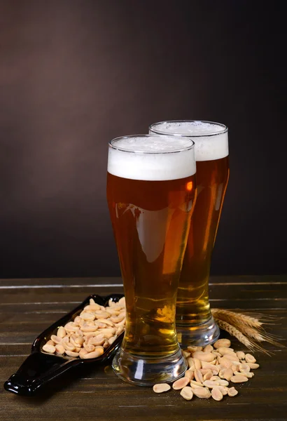 Vasos de cerveza con merienda en la mesa sobre fondo oscuro —  Fotos de Stock