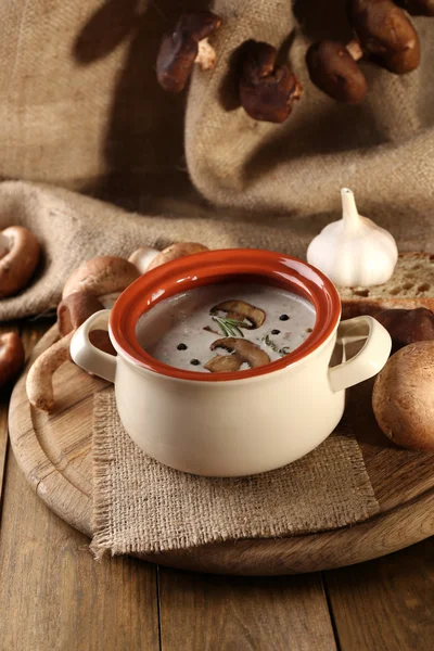 Mushroom soup in pot, on wooden table, on sackcloth background — Stock Photo, Image