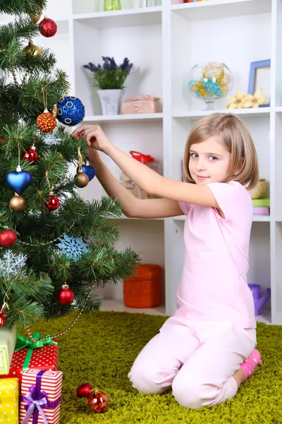 Lilla tjej dekorera julgran i rum — Stockfoto