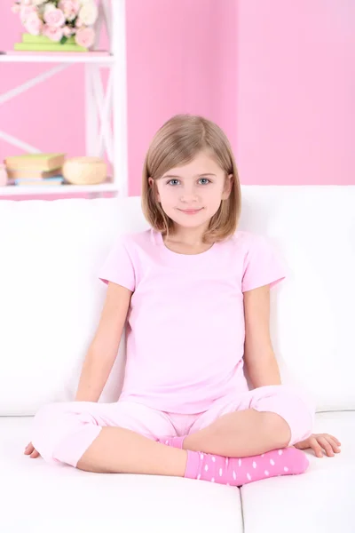 Little girl sitting on sofa in room — Stock Photo, Image