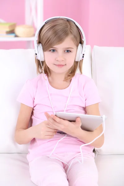 Bambina seduta sul divano ad ascoltare musica in camera — Foto Stock