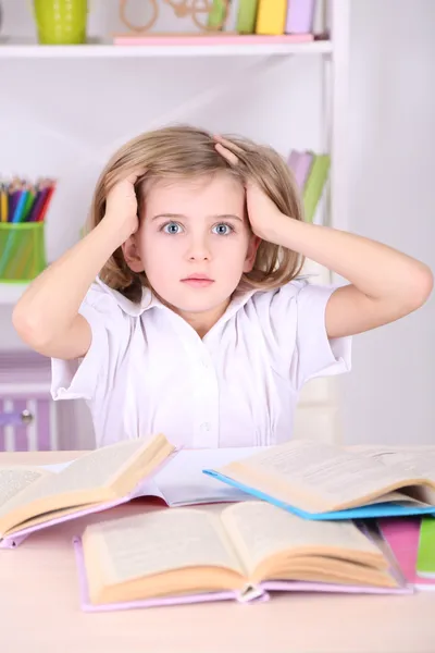 Little girl sitting at desk in room — Stock Photo, Image