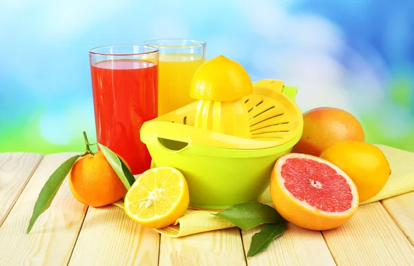 Citrus press and fruits on table on blue background — Stock Photo, Image