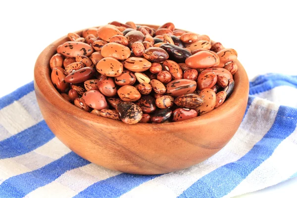 Raw beans in bowl on color napkin, isolated on white — Stock Photo, Image