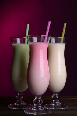 tablodaki koyu pembe bir arka plan üzerinde süt sallar