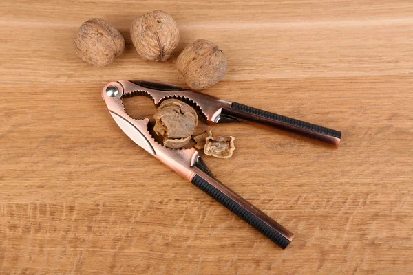 Louskáček a ořechy na dřevěném pozadí — Stock fotografie