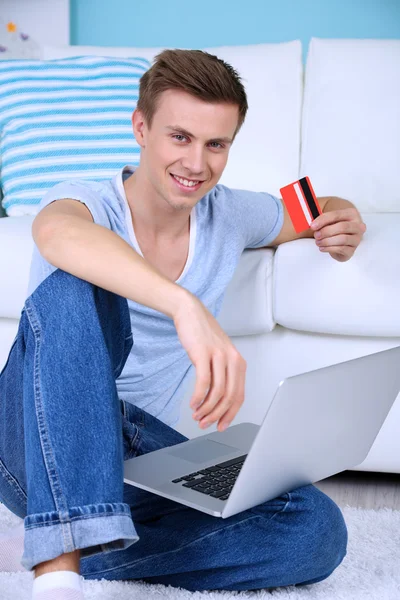 Cara sentado no chão com laptop no fundo do quarto — Fotografia de Stock