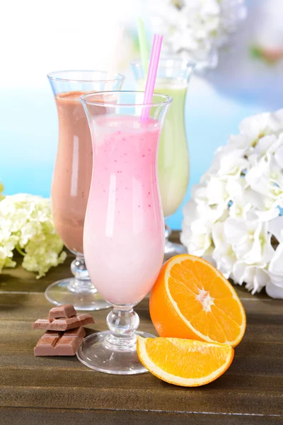 Mléčné koktejly s ovocem na tabulce na světle modrém pozadí — Stock fotografie