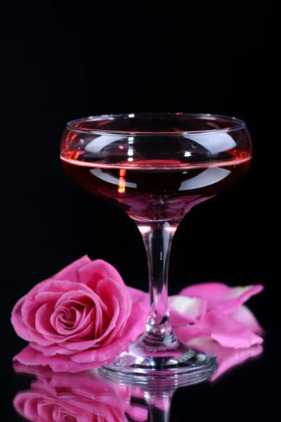 Sammansättning med rosa gnistra vin i glas och rose isolerade på svart — Stockfoto