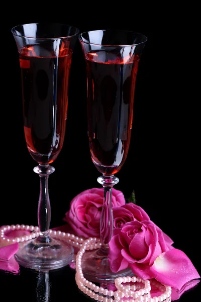Samenstelling met roze wijn in glazen en rozen geïsoleerd op zwart — Stockfoto