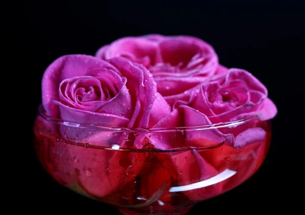 ピンクの輝きのワインと黒に分離されたガラスのバラと組成 — ストック写真