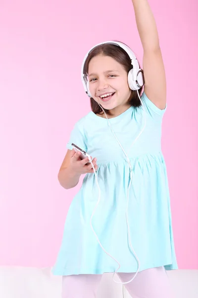 Bella bambina che ascolta musica e danza sul divano e ascolta musica, sullo sfondo interno di casa — Foto Stock