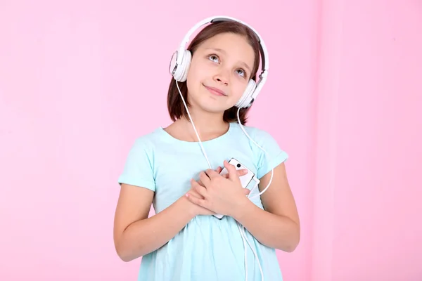 Beautiful little girl listening to music and dancing on sofa  and listening to music, on home interior background — Stock Photo, Image