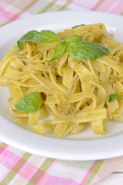 Läckra pasta med pesto på tallriken på bordet närbild — Stockfoto