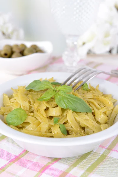 Heerlijke pasta met pesto op plaat op tafel op lichte achtergrond — Stockfoto