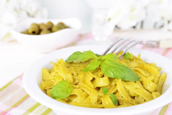 Deliciosa pasta con pesto en plato sobre mesa sobre fondo claro —  Fotos de Stock