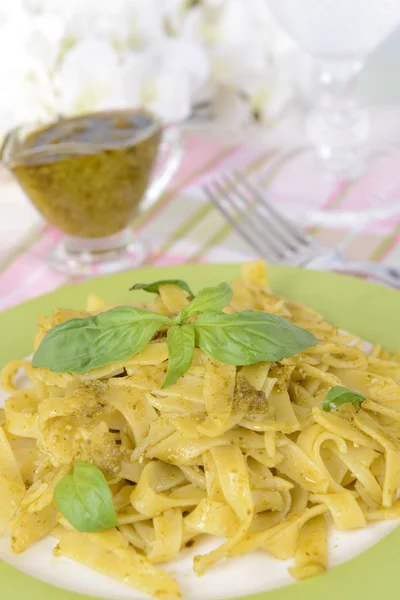 Pyszny makaron z pesto na talerz na stole na jasnym tle — Zdjęcie stockowe