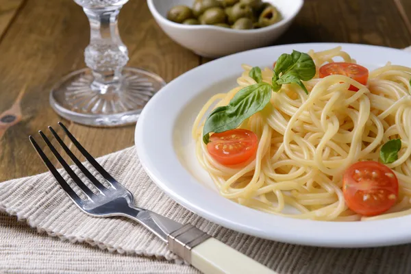 Deliciosos espaguetis con tomates en plato en la mesa de primer plano —  Fotos de Stock